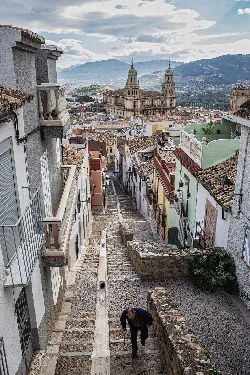 Steep street in the Jewish quarter of Jaén with cathedral and mountains in the background.