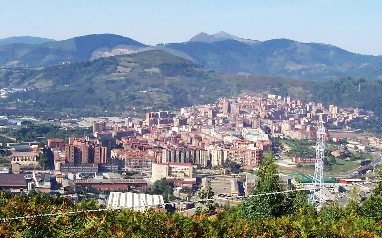Vista aérea de Basauri con edificios y montañas en el horizonte.