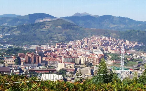 Vista aérea de Basauri con edificios y montañas en el horizonte.