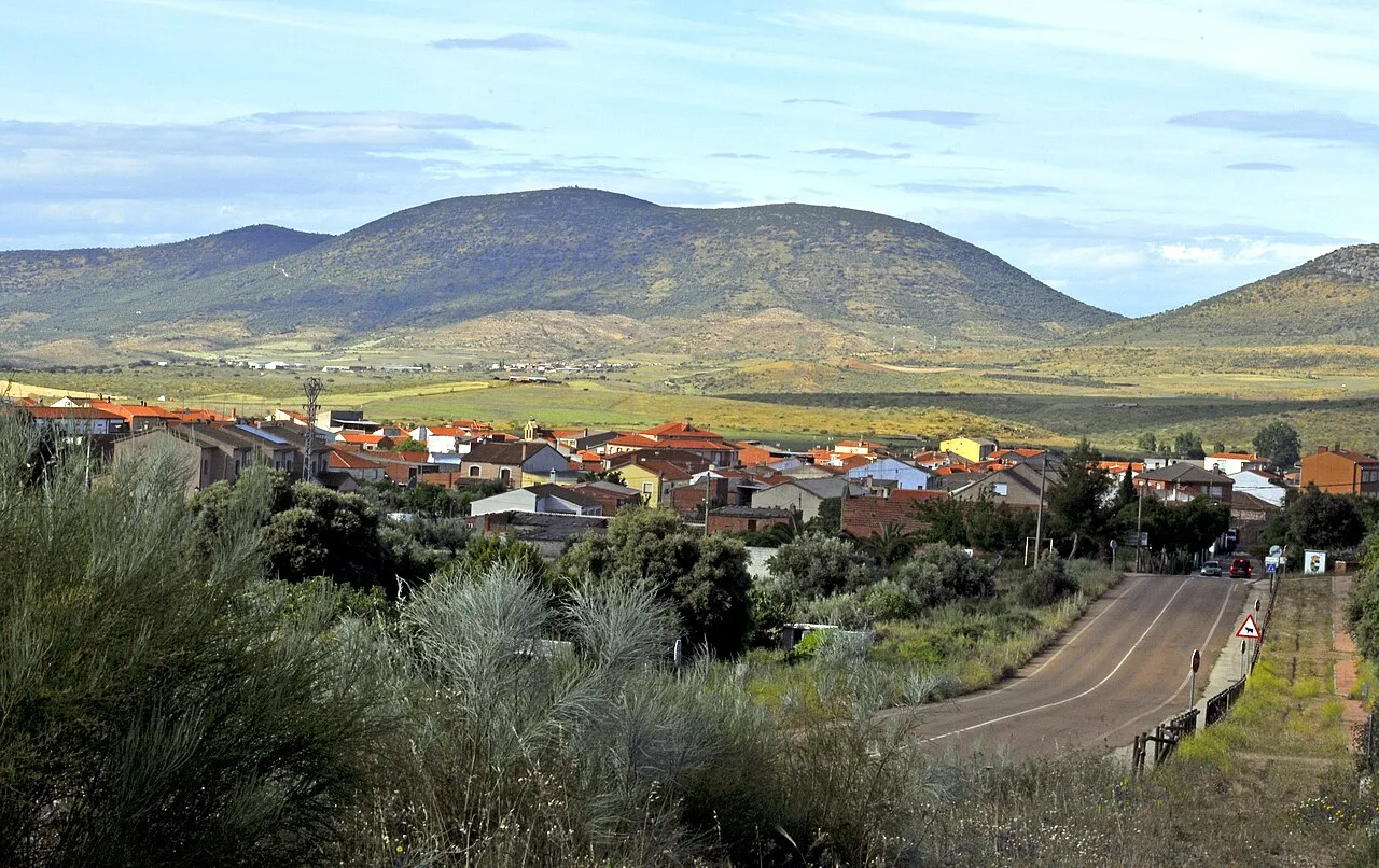 Dorf mit Häusern und Bergen im Hintergrund, von der Straße aus gesehen.