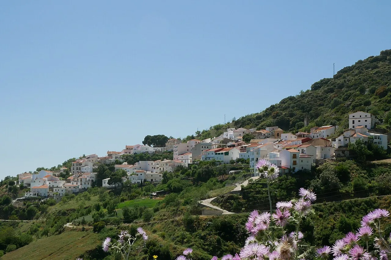 Pueblo de Polopos con casas blancas en una ladera y vegetación.