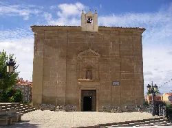 Fachada de la basílica de San Marcial en Lardero con puertas de madera y una pequeña campana en la parte superior.