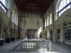 Interior of Canfranc station hall with aged walls and tall windows.