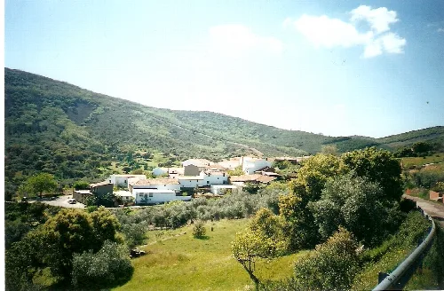 View of white houses and trees in a mountainous landscape.