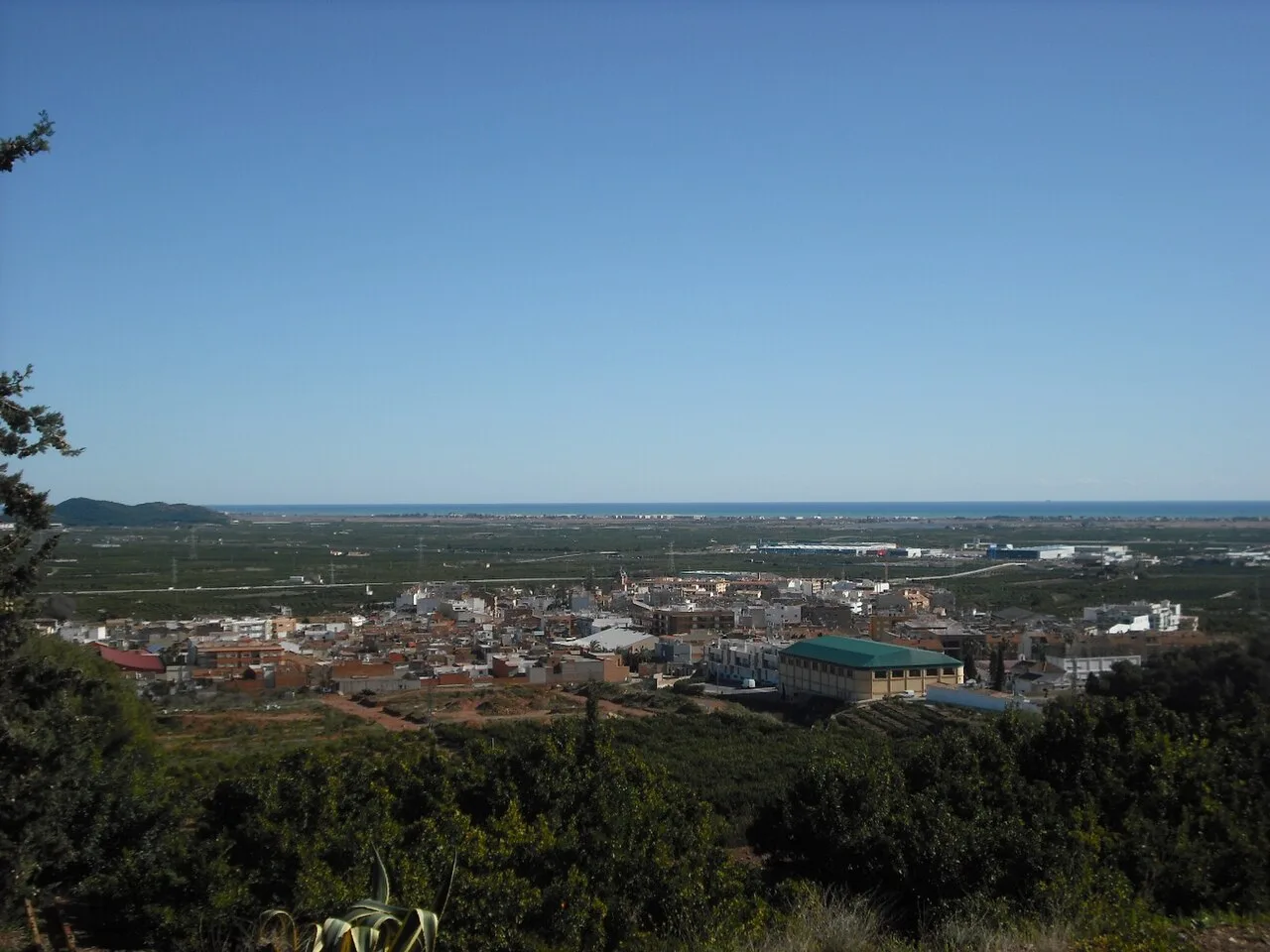 Landschaft mit einer Stadt und offenen Feldern am Horizont.