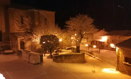 Plaza con árboles y farolas en Aras, Navarra, de noche.