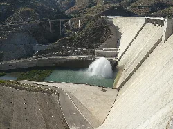 Puente y presa en Vélez de Benaudalla con agua y montañas.