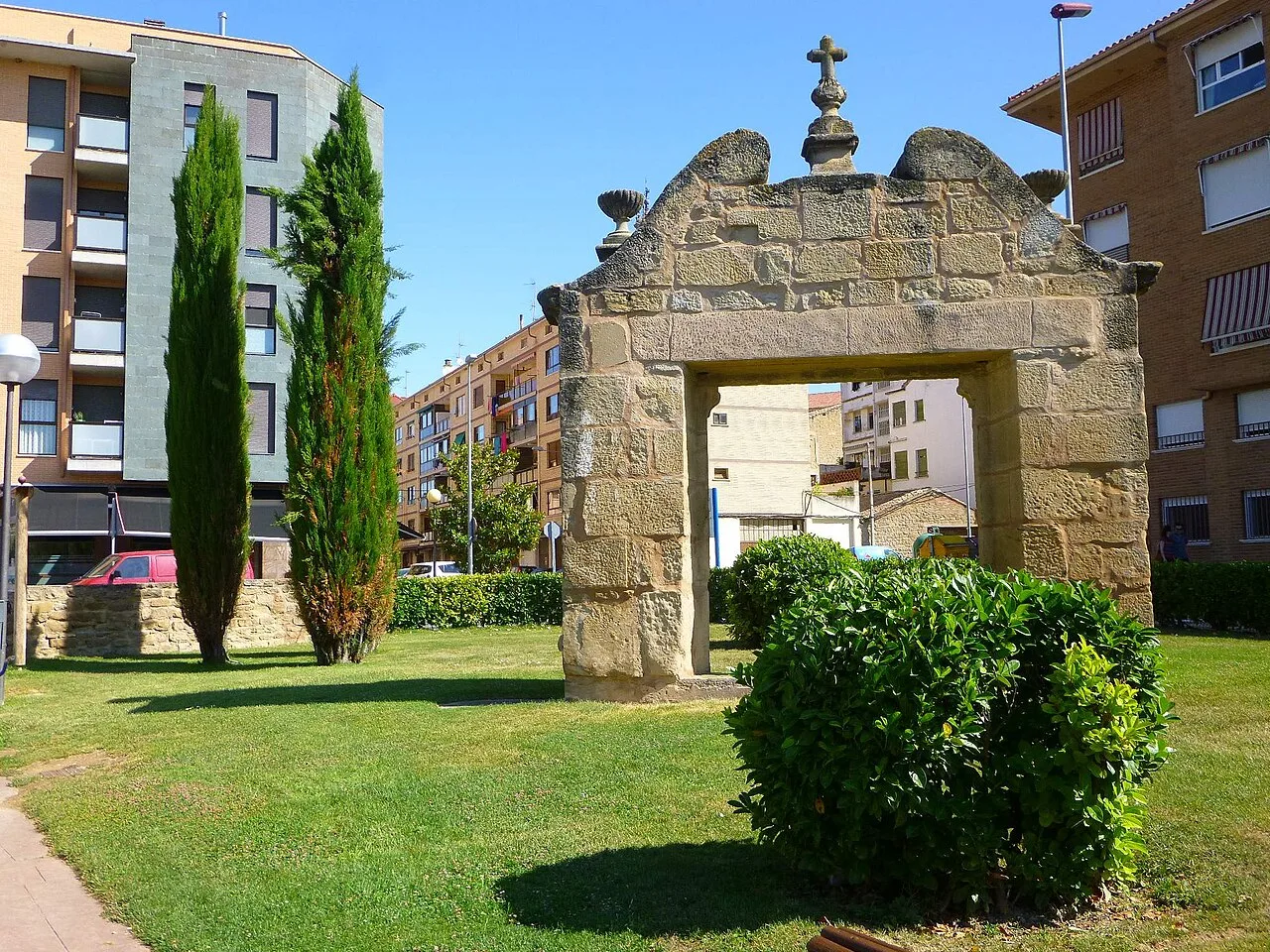 Arco de piedra en un parque con árboles y edificios alrededor en Oyón.