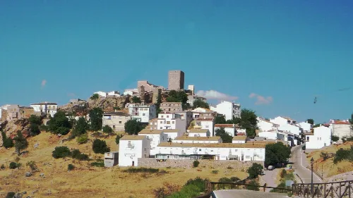 Blick auf eine Stadt mit weißen Häusern und einer Burg auf einem Hügel.