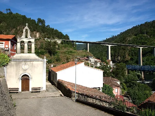 Weiße Kapelle mit Kreuz in Os Peares, mit Brücke in den Bergen.