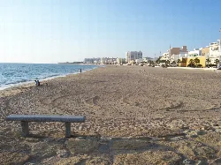 Playa de arena con edificios y palmeras en Rota, Cádiz.