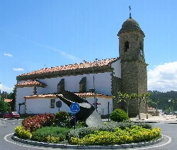 St. Peter's church in Sopelana with clock and garden with sculptures.