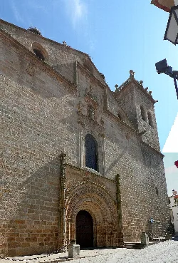 Steinerne Fassade einer Kirche mit Bogenportal und Turm in Brozas.