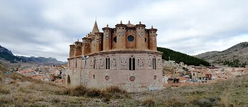 Blick vom Chor einer mittelalterlichen Kirche in Montalbán, mit Türmen und Berglandschaft.