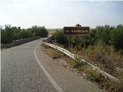 Puente de piedra sobre el río Guadarrama con vegetación a los lados.