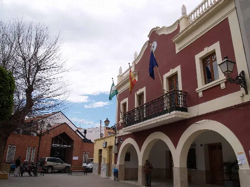 Edificio del ayuntamiento con arcos y banderas en Viator, Almería.