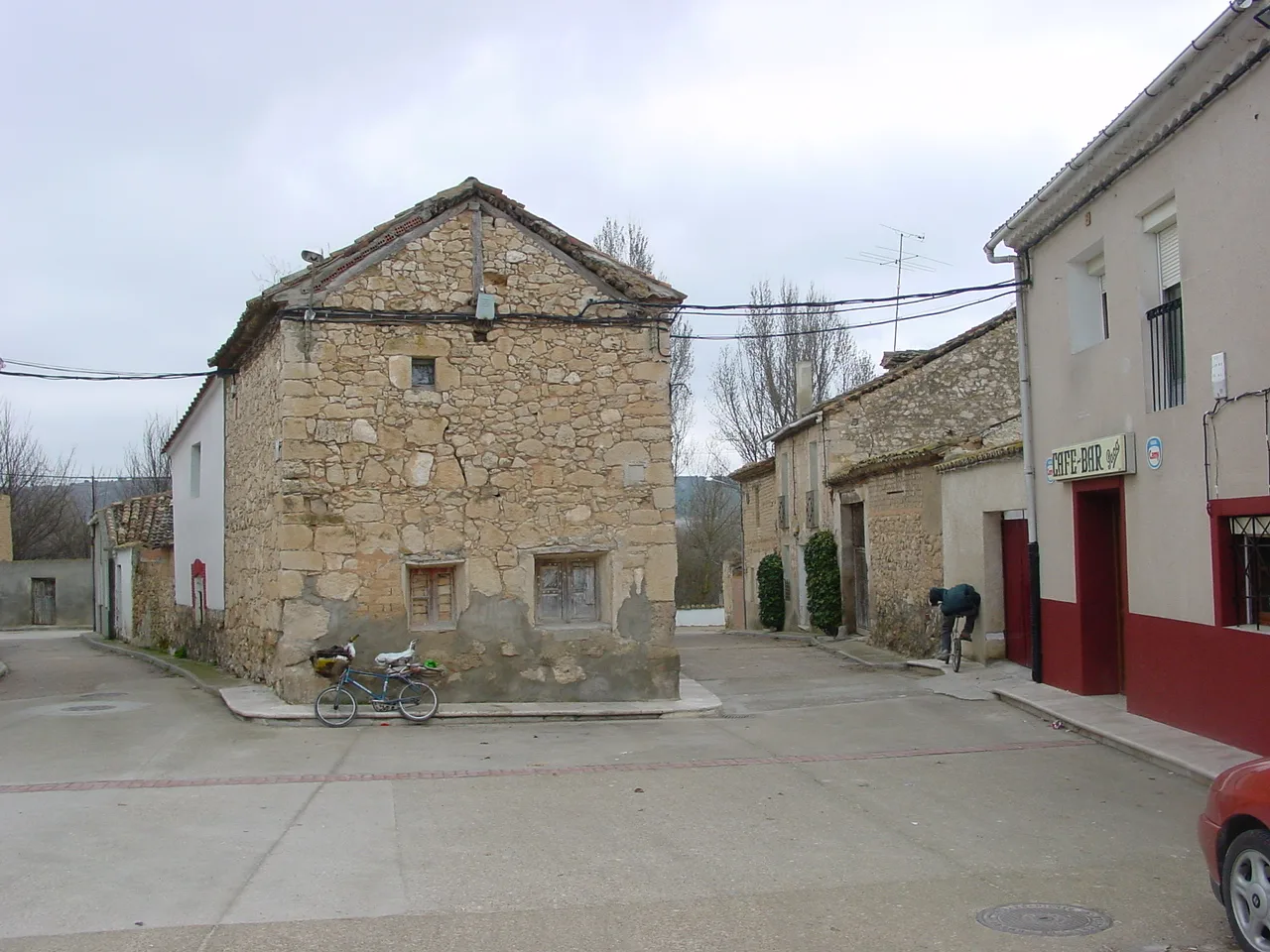 Old and modern houses on a street in Valbuena de Duero, Valladolid, with a cyclist and a bar.