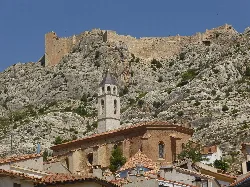 Iglesia de San Miguel con torre y castillo en lo alto de la colina.