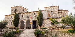 Steinfassade der Kirche San Sebastián in Pioz mit Bögen und Bäumen.