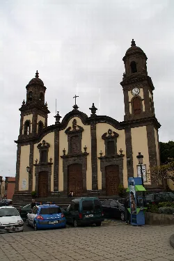 Fassade einer Kirche mit zwei Türmen und einer Uhr auf einem Platz.