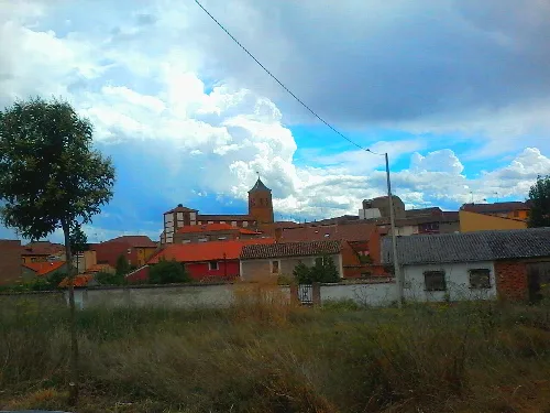 Häuser und eine Kirche in Valdevimbre, León, mit bewölktem Himmel.