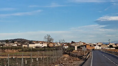 Landschaft von Villanueva Mesía gesehen von der Straße mit Häusern und blauem Himmel.