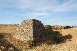 Steinruinen eines Forts in einem offenen Feld mit blauem Himmel.