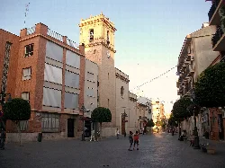 Platz in Mislata mit geschnittenen Bäumen und einer Kirche im Hintergrund.