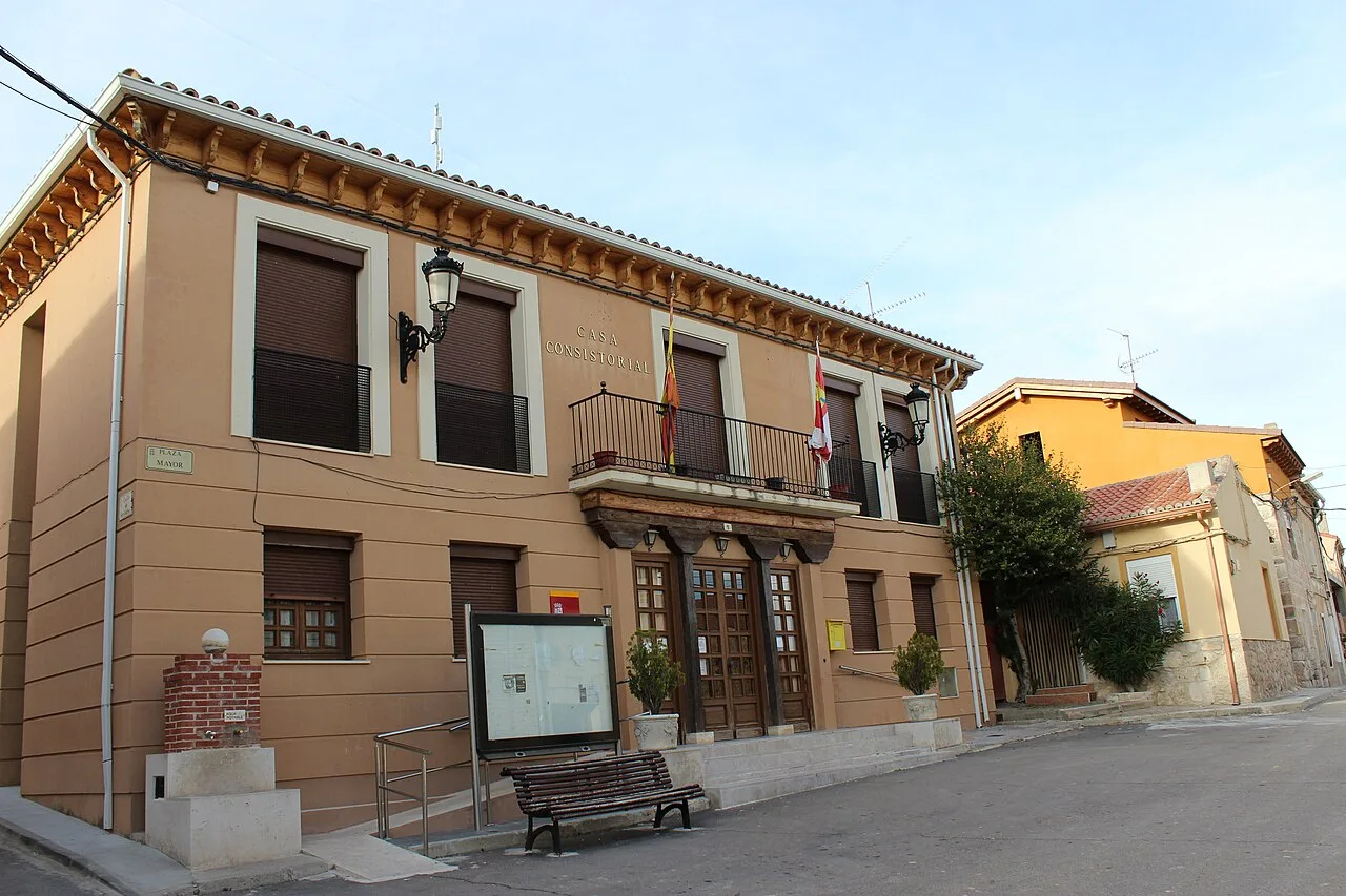 Town hall building with beige facade and dark-shuttered windows.