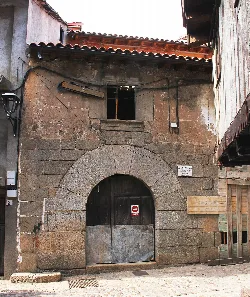 Stone facade with arch and wooden door in Cepeda, Salamanca.