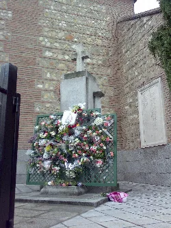 Cruz de piedra con flores y ofrendas en Fuencarral, Madrid.