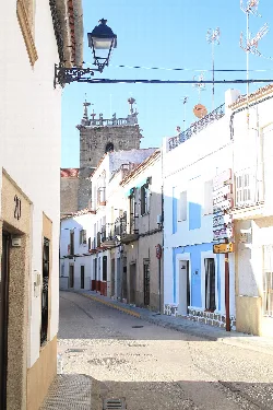 Narrow streets with white houses and a church in the background in Casar de Cáceres