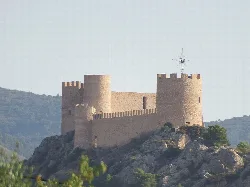 View of a castle on a hill with towers and stone walls.