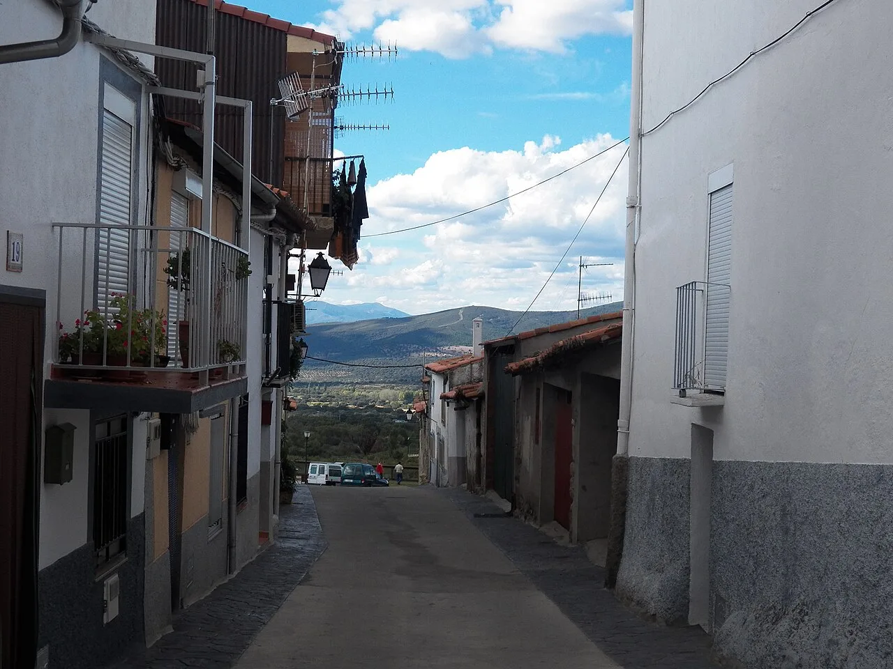 Enge Straße mit Häusern und Bergblick im Hintergrund.