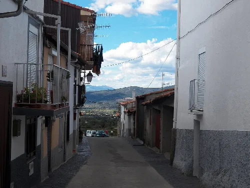 Enge Straße mit Häusern und Bergblick im Hintergrund.