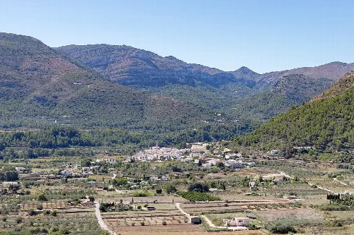 Landschaft mit Bergen und einem Dorf im Tal.