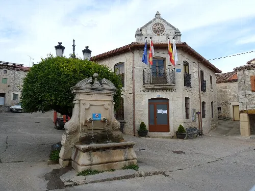 Town hall building with flags and fountain in the square.