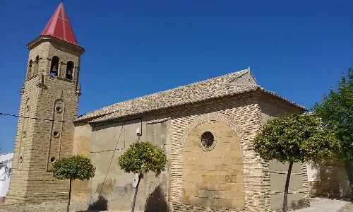 Steinernes Kirchengebäude mit Turm und Bäumen in Lahiguera.