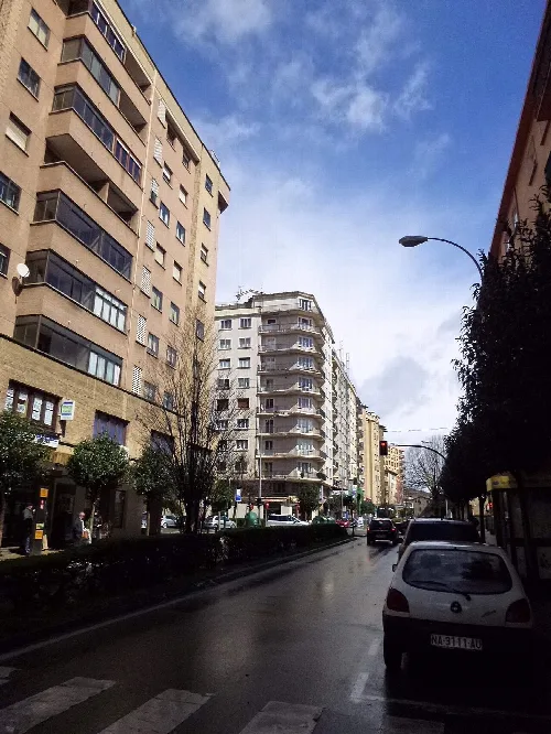 Städtische Straße in Burlada mit Gebäuden und Bäumen.