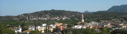 Landschaft von Algimia de Alfara mit Bergen und Gebäuden im Vordergrund.