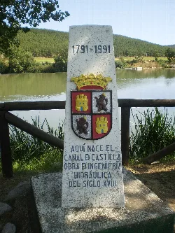 Memorial stone with dates and coats of arms near a river in Alar del Rey.