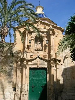 Facade of a church with columns, statues, and a green door.