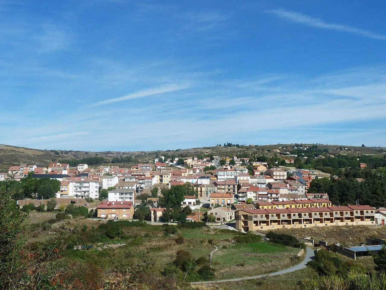 Panoramablick auf Peguerinos mit Häusern und Hügeln im Hintergrund.