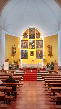 View of the interior of a church with altar and religious paintings in the background.