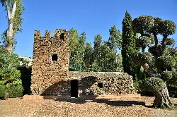 Stone Milk Tower in a park with trees and grass.