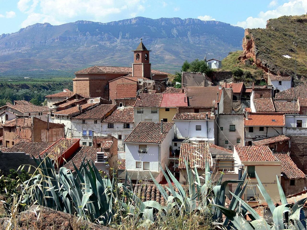 View of houses and a church in Herce, La Rioja, with mountains in the background.