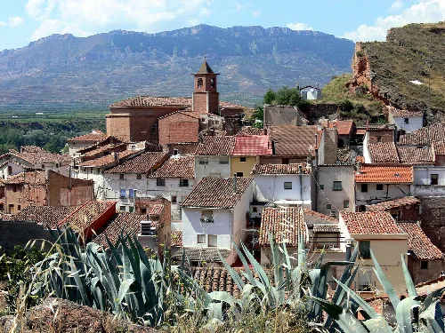 Vista de casas y una iglesia en Herce, La Rioja, con montañas al fondo.