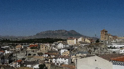 Blick auf Häuser und einen Glockenturm mit einem Berg im Hintergrund