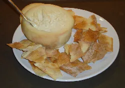 Torta del Casar cheese with toasts on a white plate.