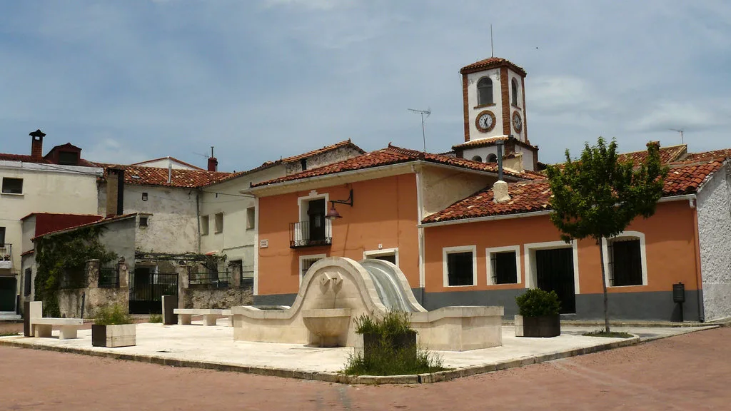 Plaza del pueblo con fuente y casas con tejados rojos en Las Majadas.